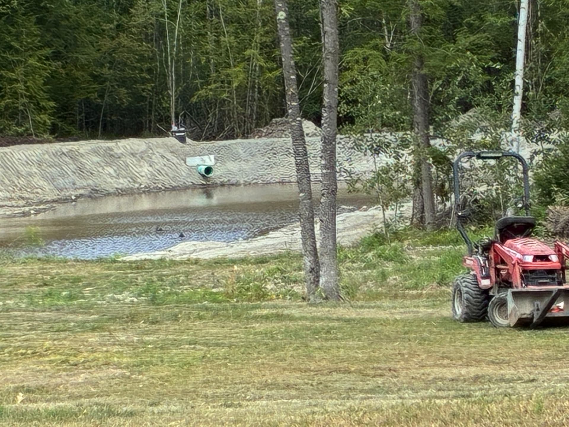 Finished pond bank with outlet pipe installed and the surrounding field mowed