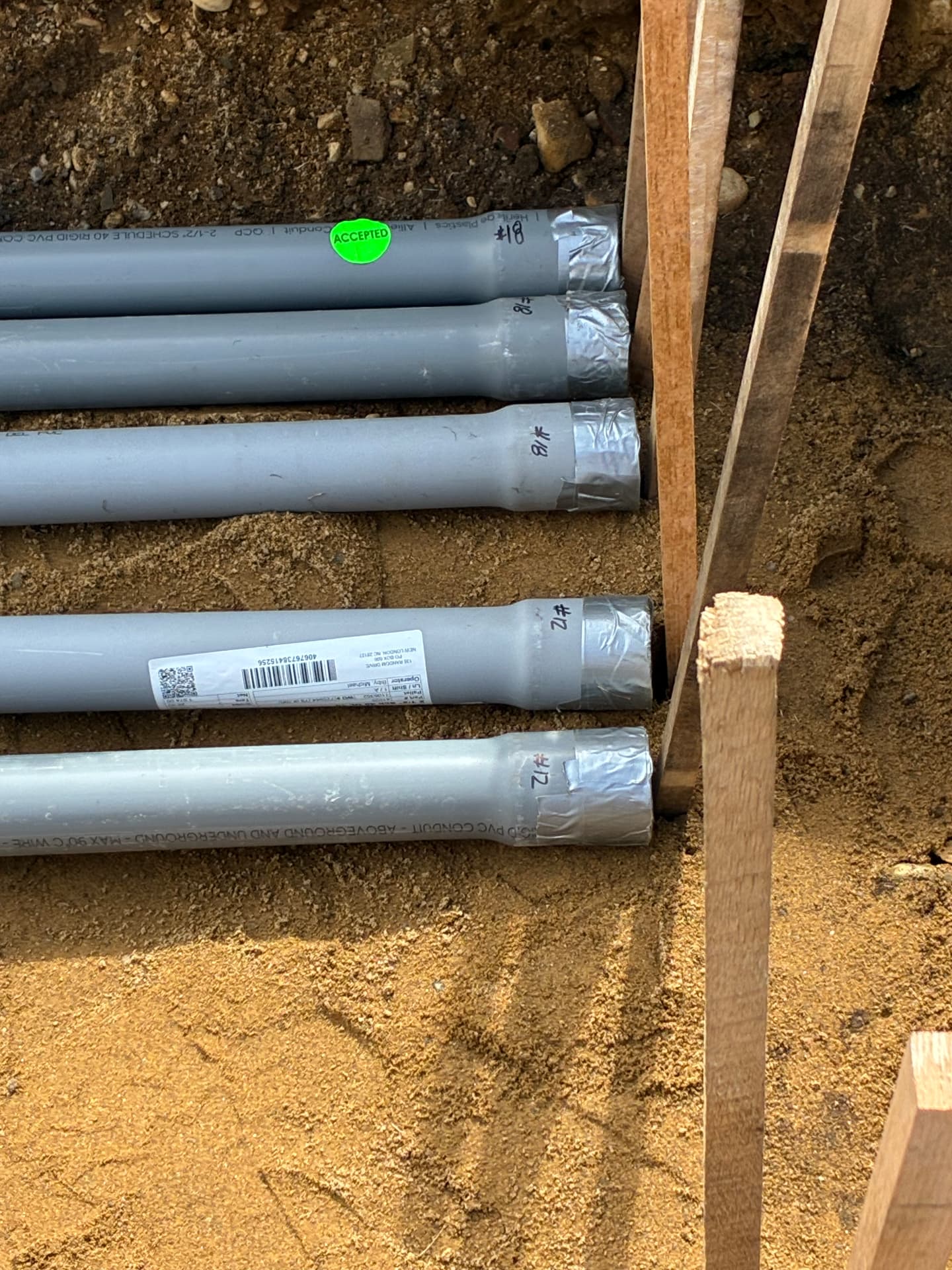 Labeled PVC conduit runs bedded in sand inside a utility trench