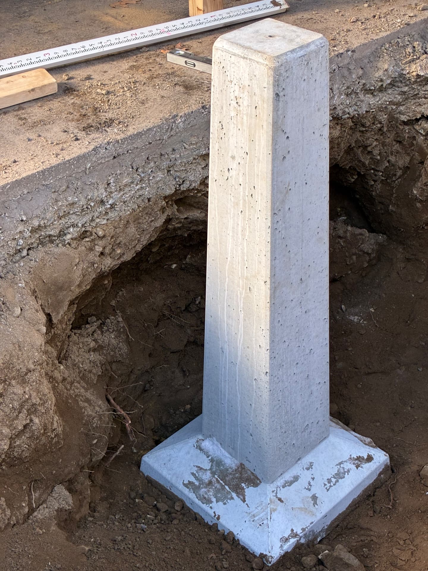 New precast concrete post base set level in a freshly excavated hole