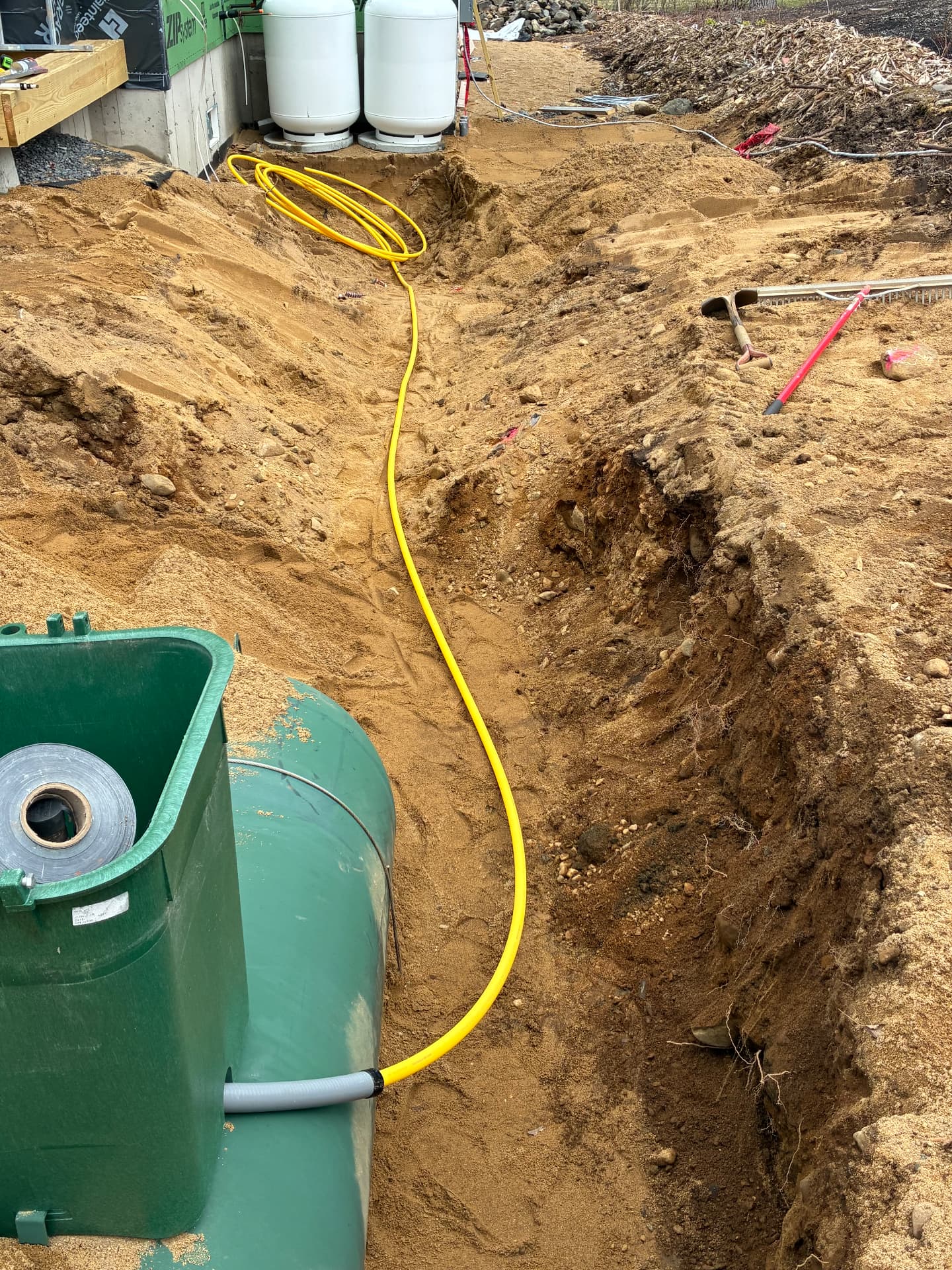 Trench dug for an underground propane tank and yellow gas line to the house