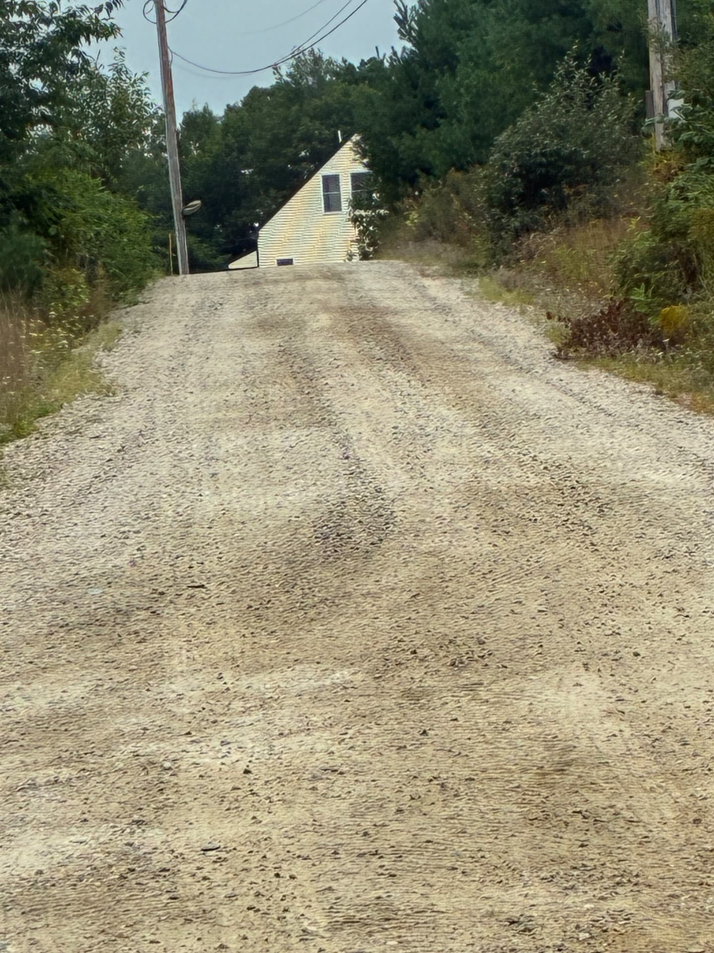 New gravel driveway arriving at the top of the hill beside the house