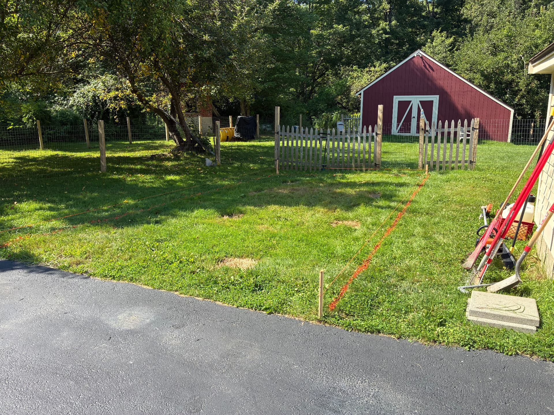 Stakes, string line, and marking paint laying out a new gravel parking pad off an existing driveway